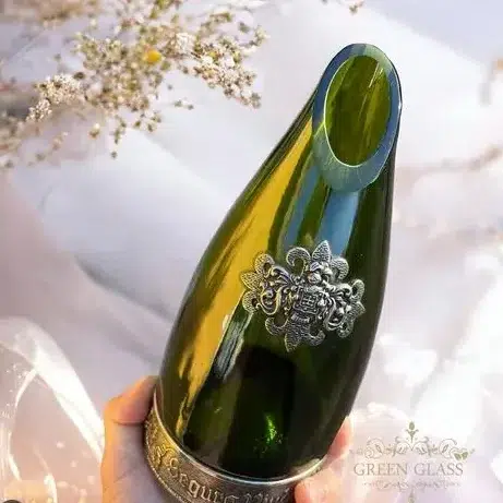 Corte diagonal artesanal en botella de vidrio verde para diseño de objetos de lujo y cristalería premium.